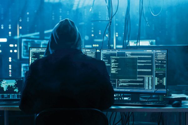 Dangerous Hooded Hacker Breaks into Government Data Servers and Infects Their System with a Virus. His Hideout Place has Dark Atmosphere, Multiple Displays, Cables Everywhere.